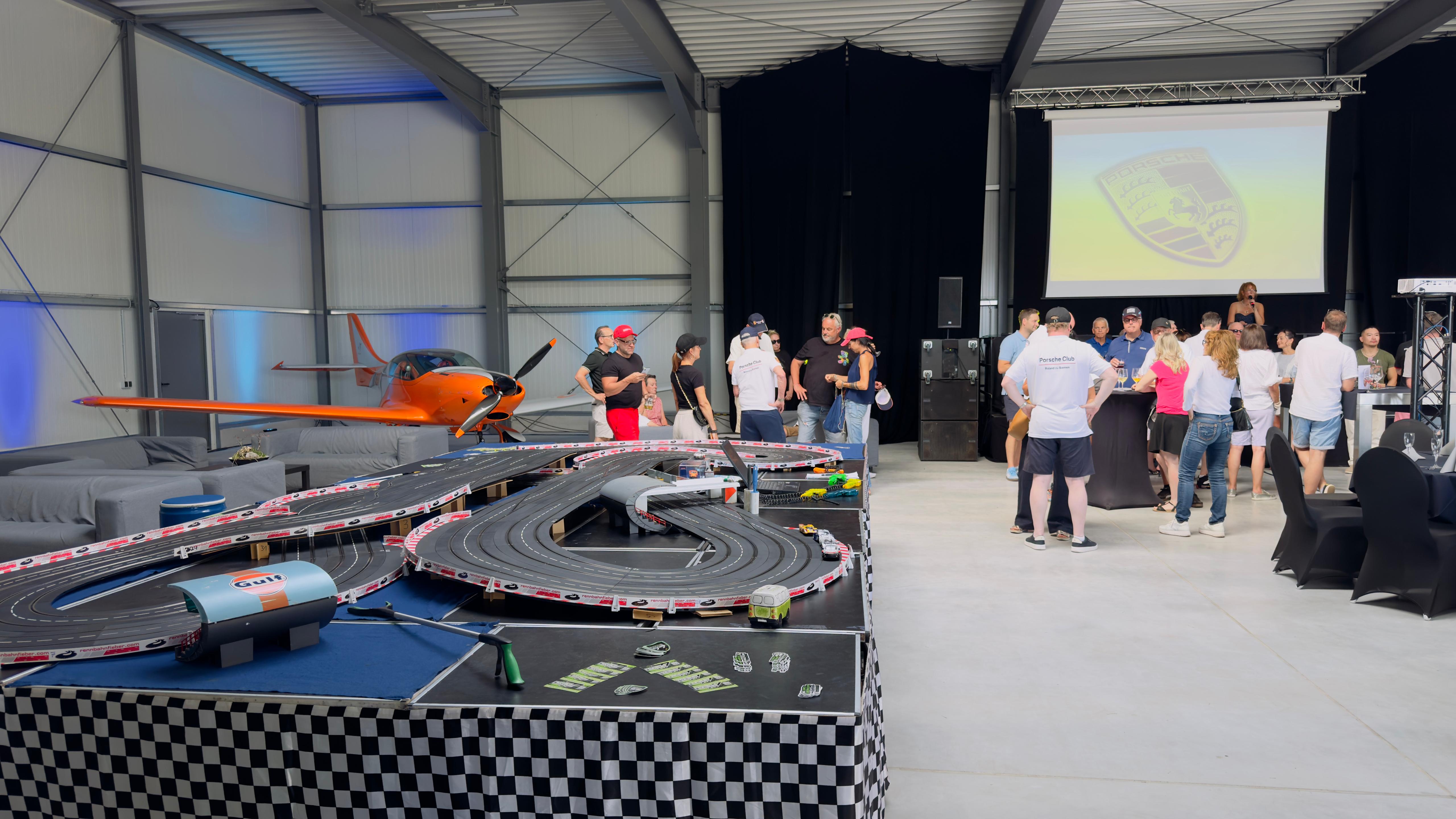 Carrera-Bahn und Flugzeug Carrera-Rennbahn der RacingLounge77 vor einem Flugzeug in der Veranstaltungshalle in Kamenz